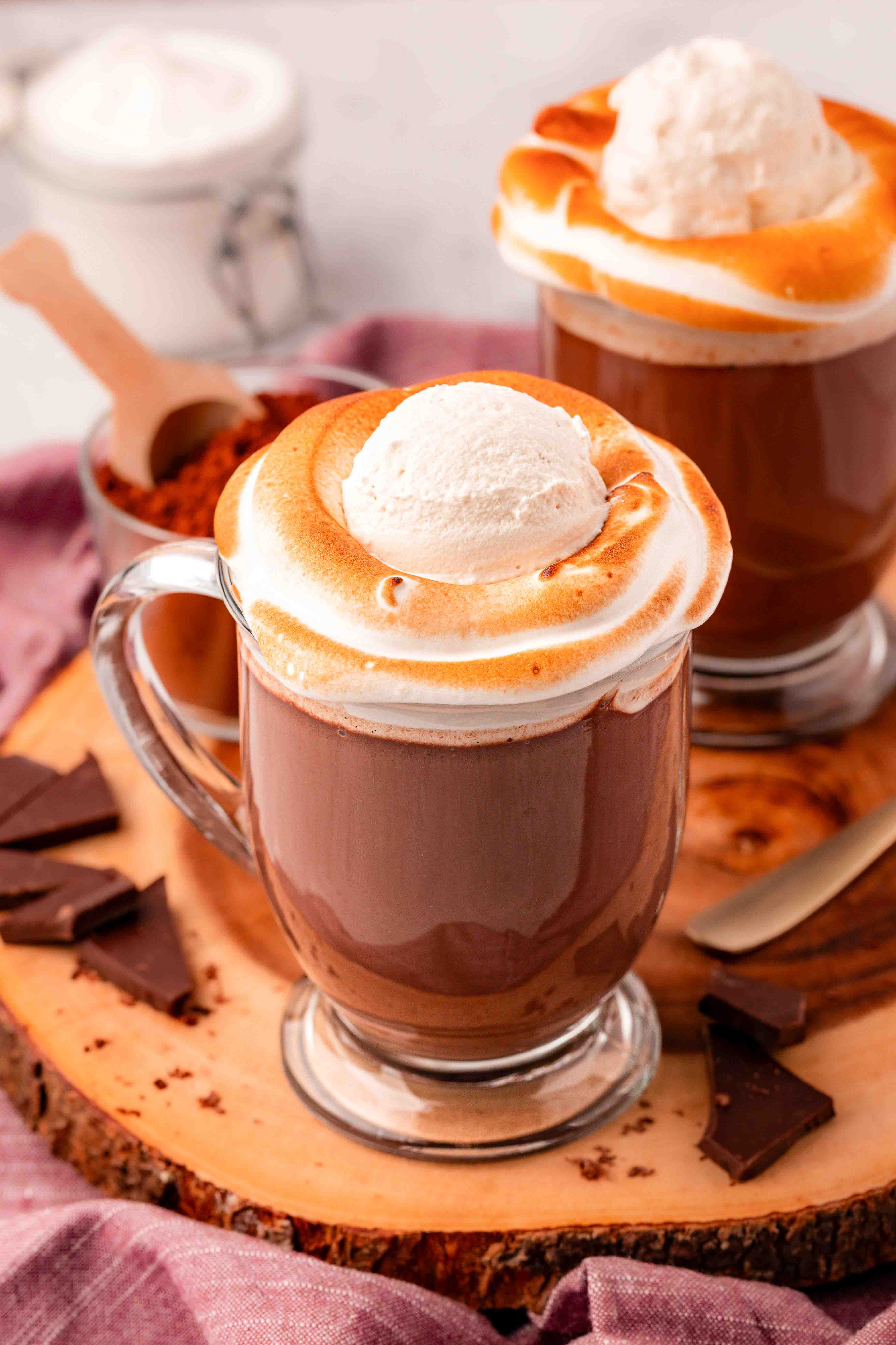 Close up of two mugs on hot chocolate with toasted fluff and whipped cream.