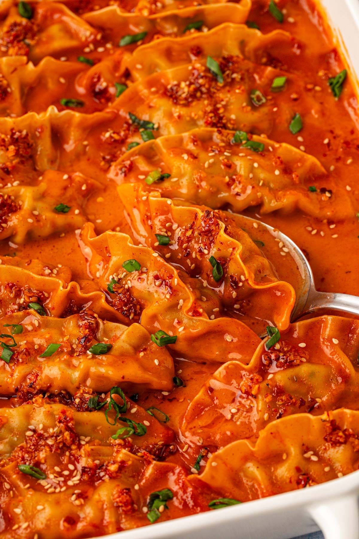 Close up of a pan of viral baked dumplings with a spoon scooping some out.