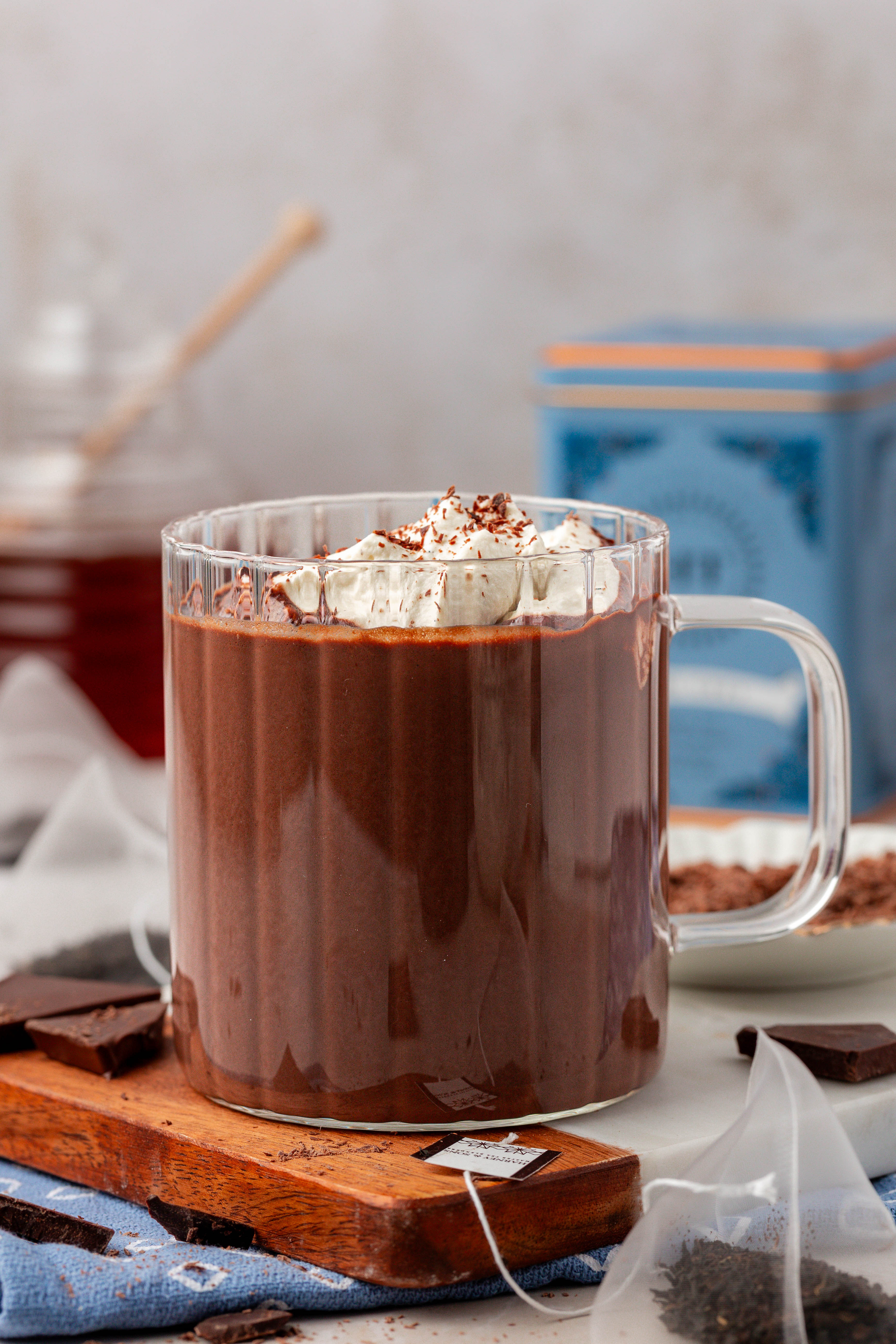 Hot chocolate in a clear mug on a wooden board.
