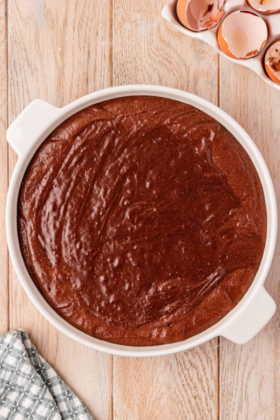 Brownie pudding batter being poured into a white baking dish.