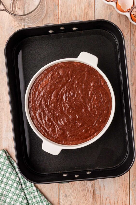 Brownie pudding batter in a dish in a water bath.