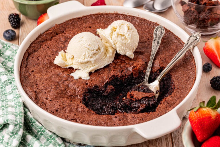Brownie Pudding with spoons in it and vanilla ice cream scoops on top.