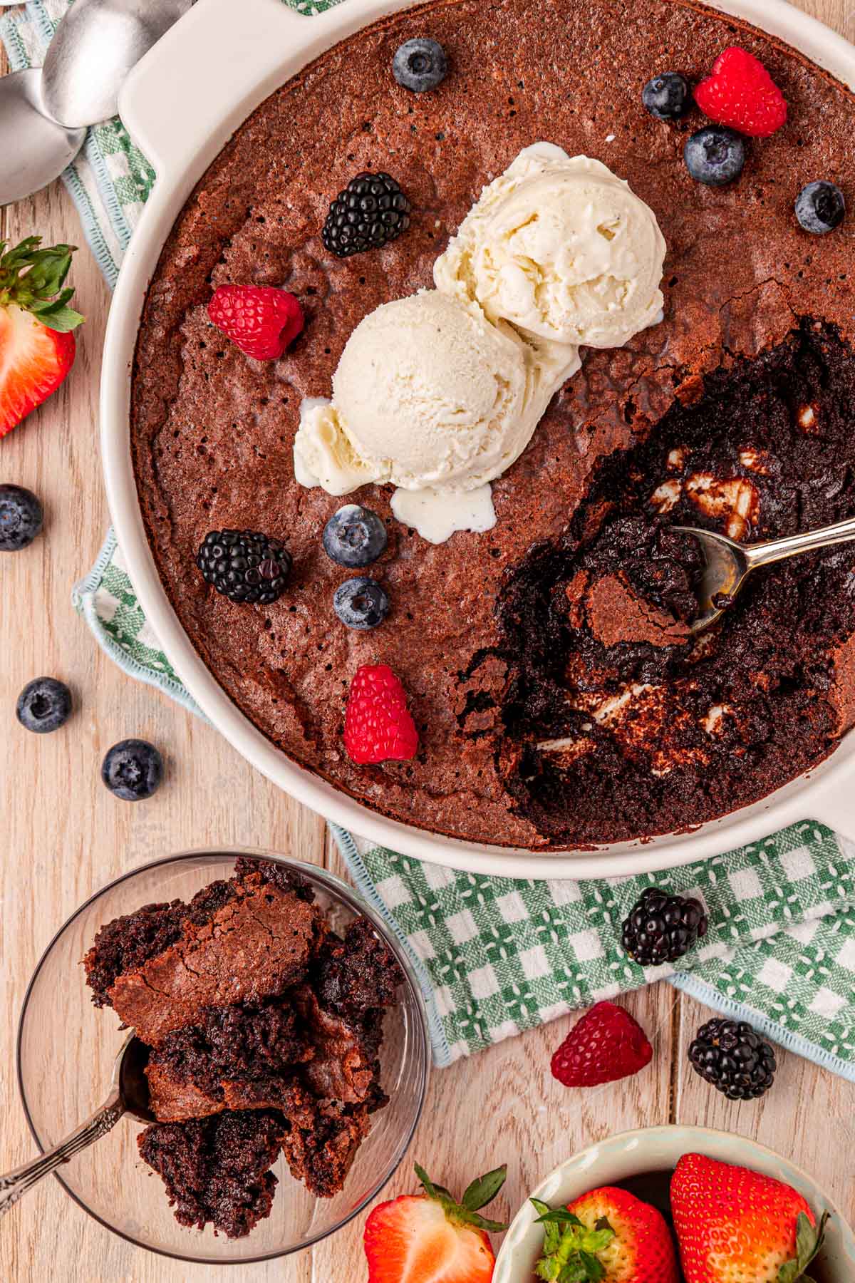 Overhead photo of a baking dish with brownie pudding topped with berries and ice cream.