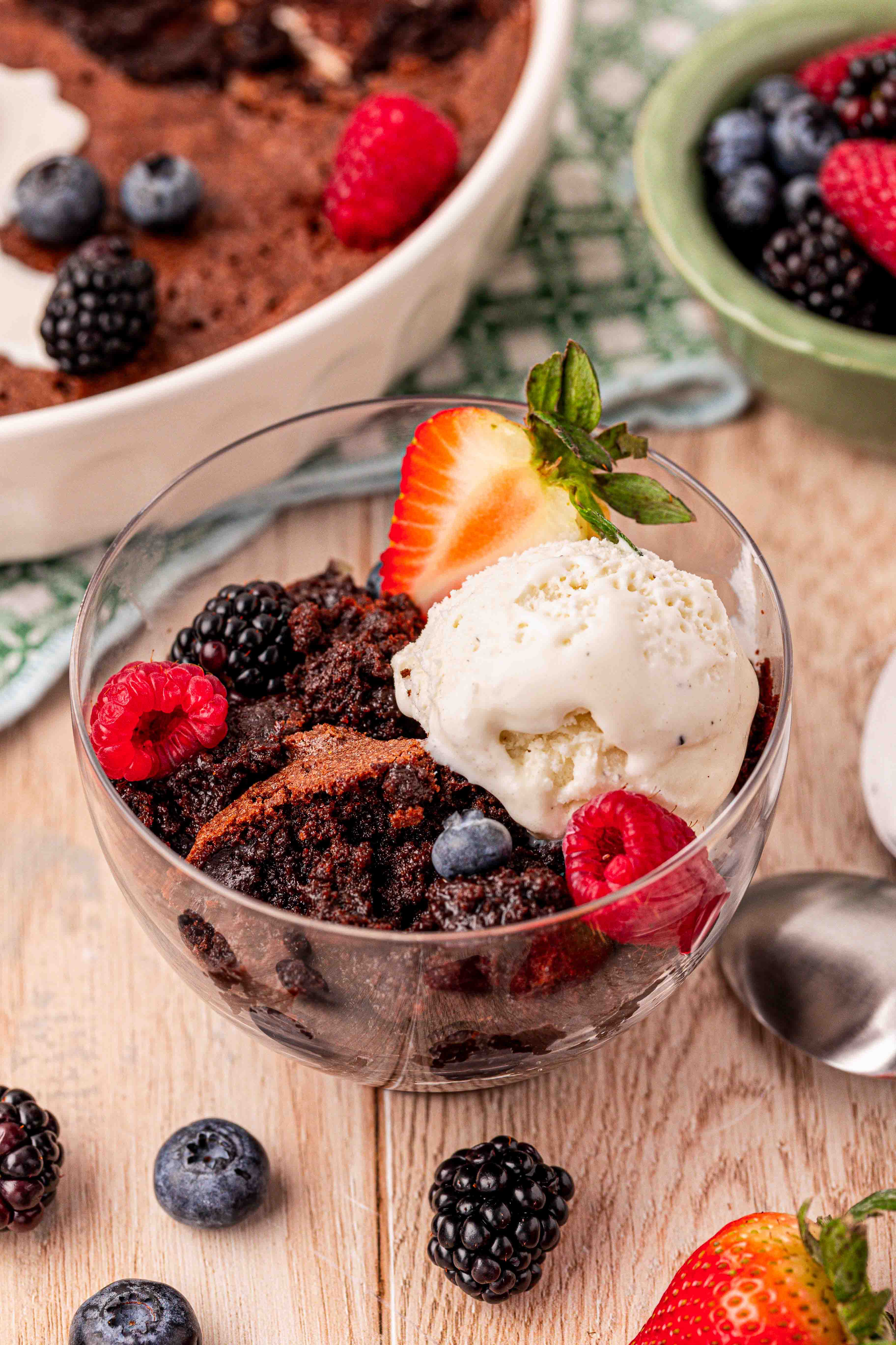A bowl of brownie pudding with a scoop of ice cream and fresh berries.