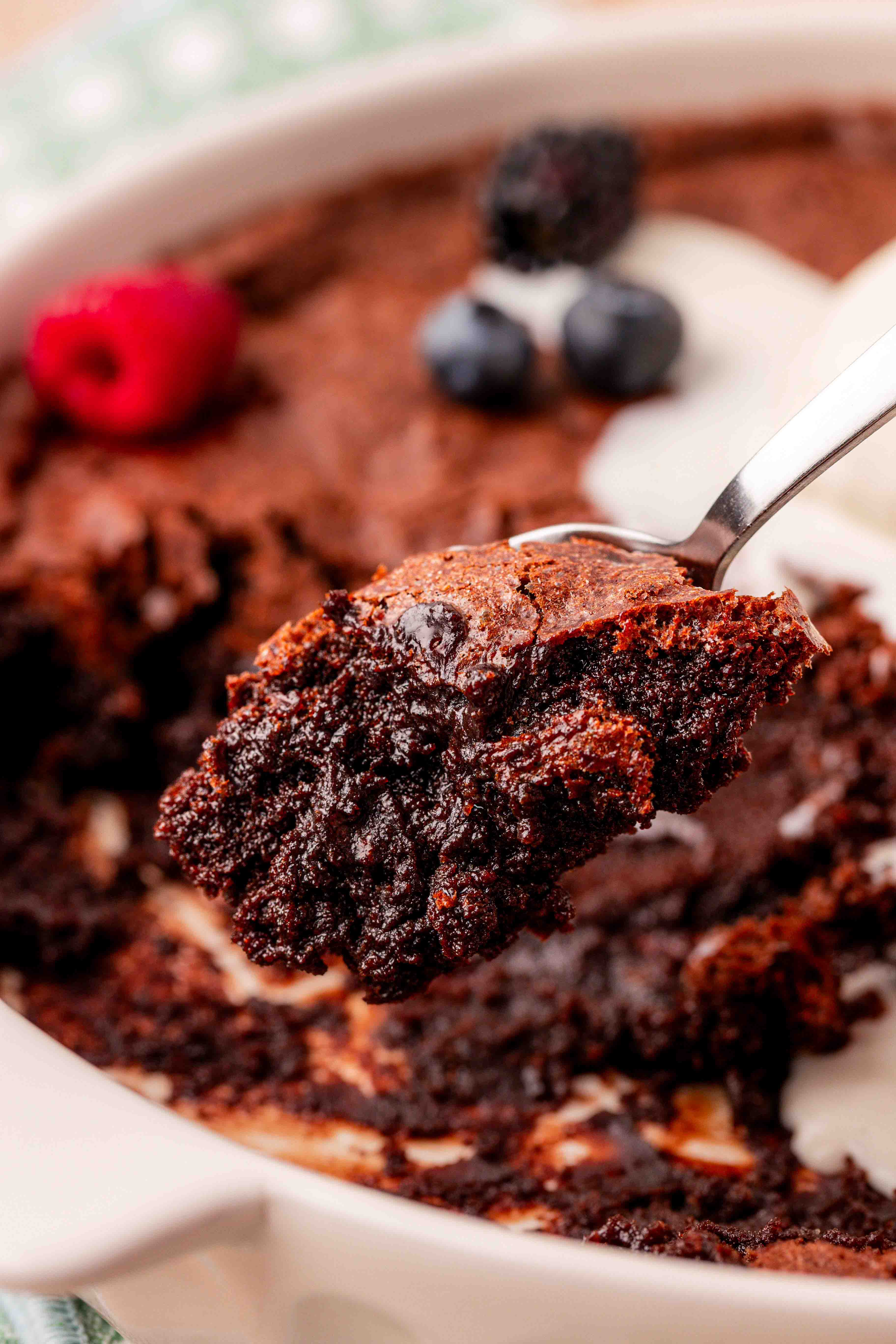Brownie pudding being spooned out of a baking dish.