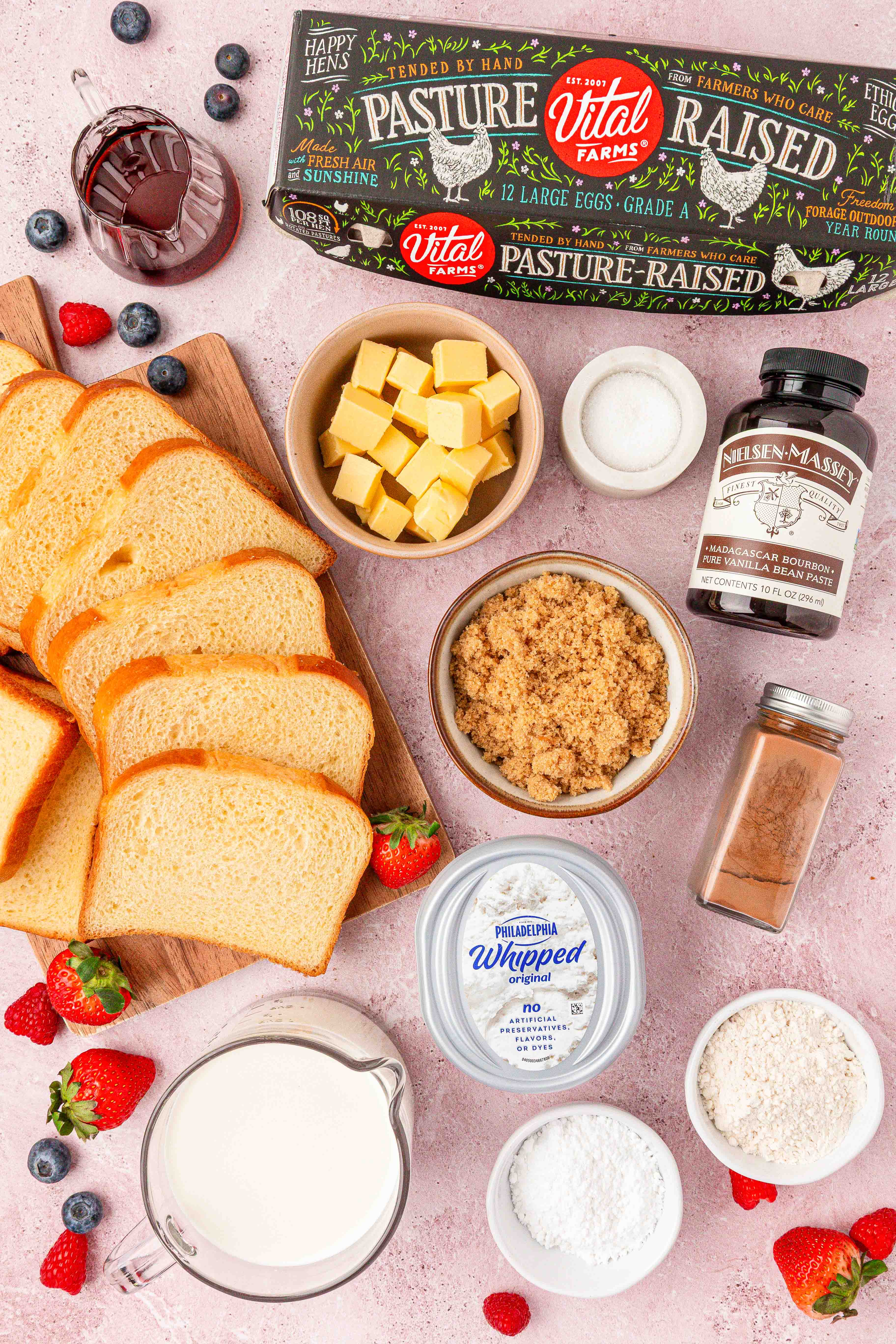 Overhead photo of ingredients to make french toast casserole on a pink table. 