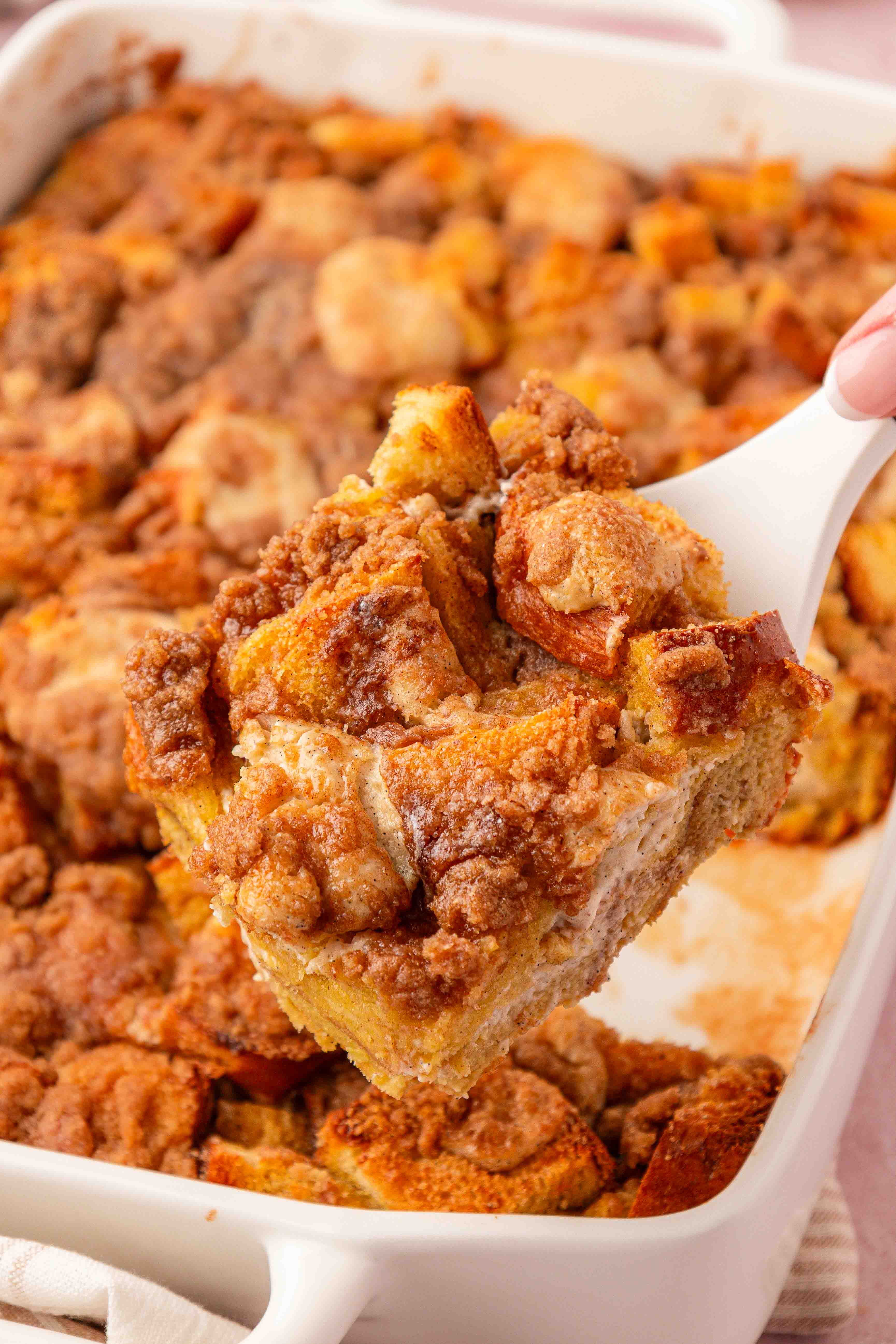 A slice of french toast casserole being lifted from the pan with a spatula.
