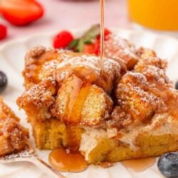A slice of french toast casserole with syrup being poured over it.