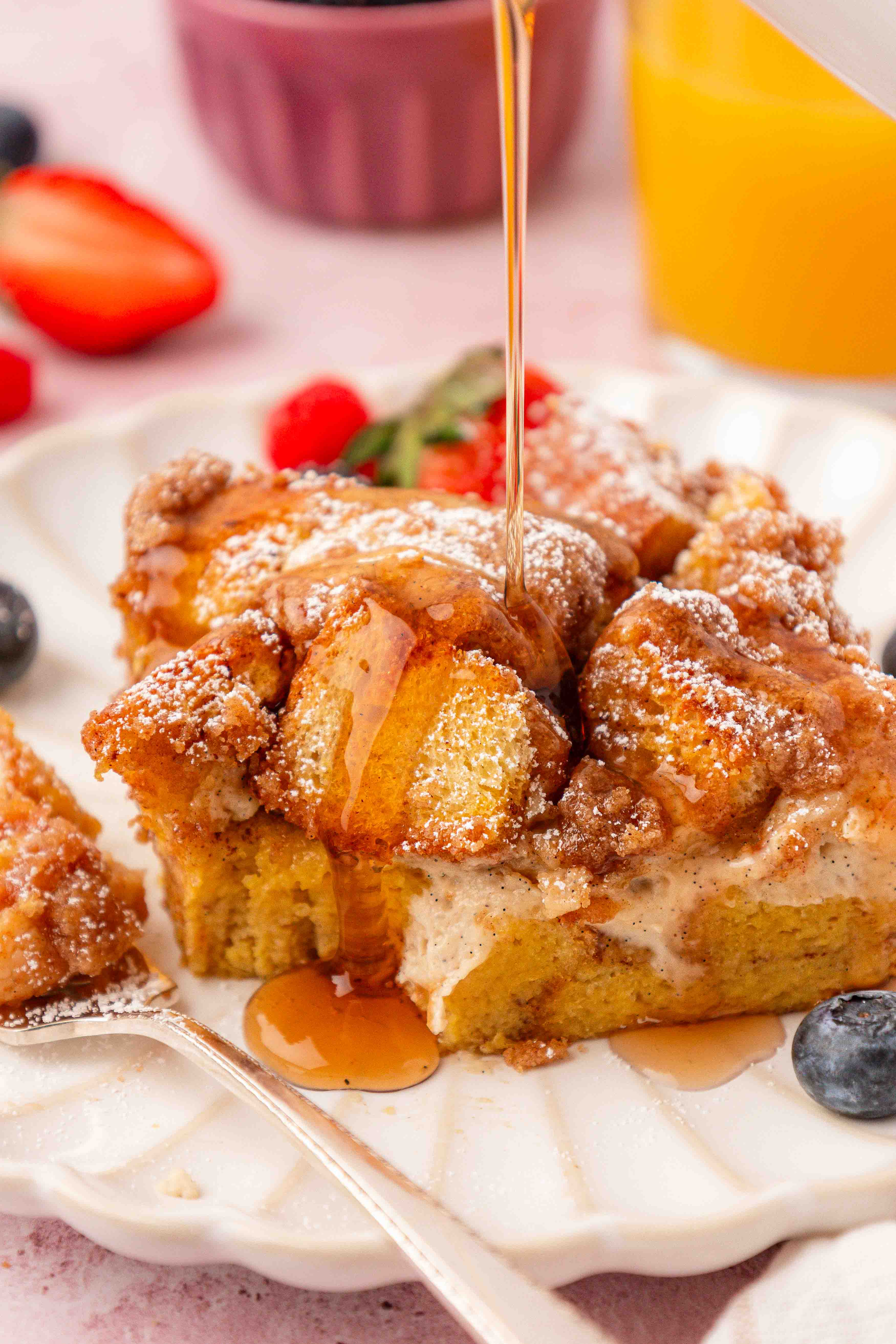 A slice of french toast casserole with syrup being poured over it.