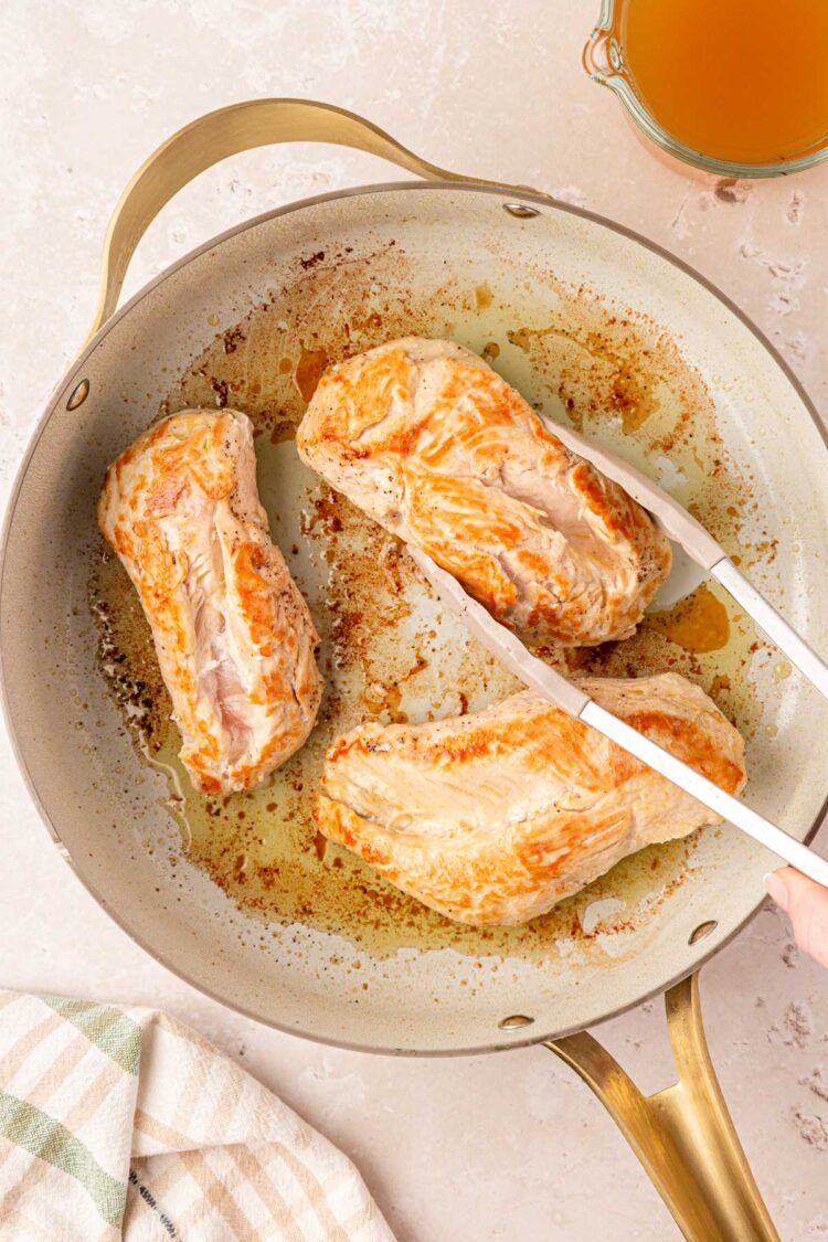 Chicken being seared in a pan.