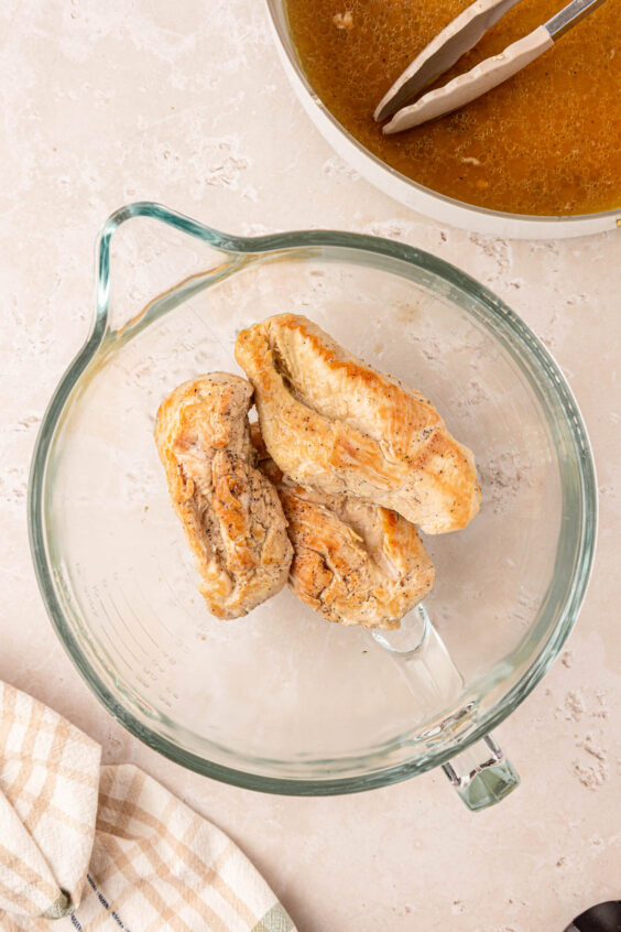 Chicken breasts in a mixing bowl to be shredded.