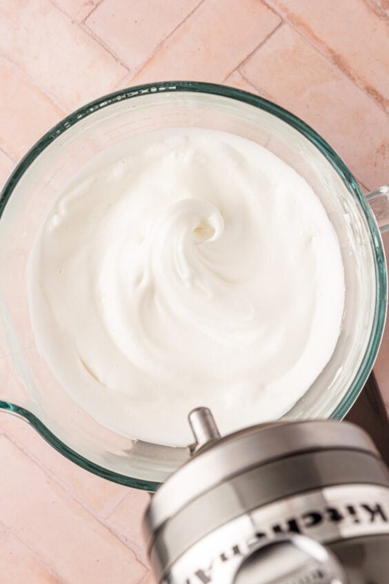 Whipped egg whites in a mixer bowl.