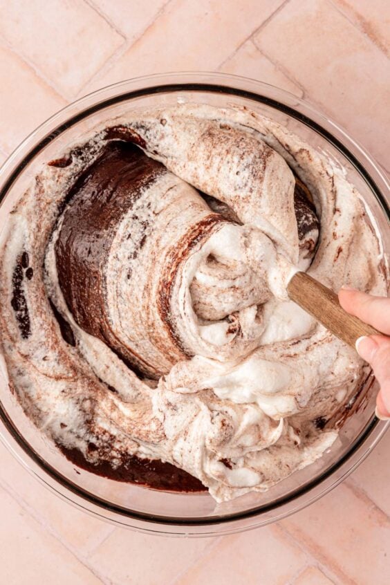 Egg whites being folded into chocolate cake batter.