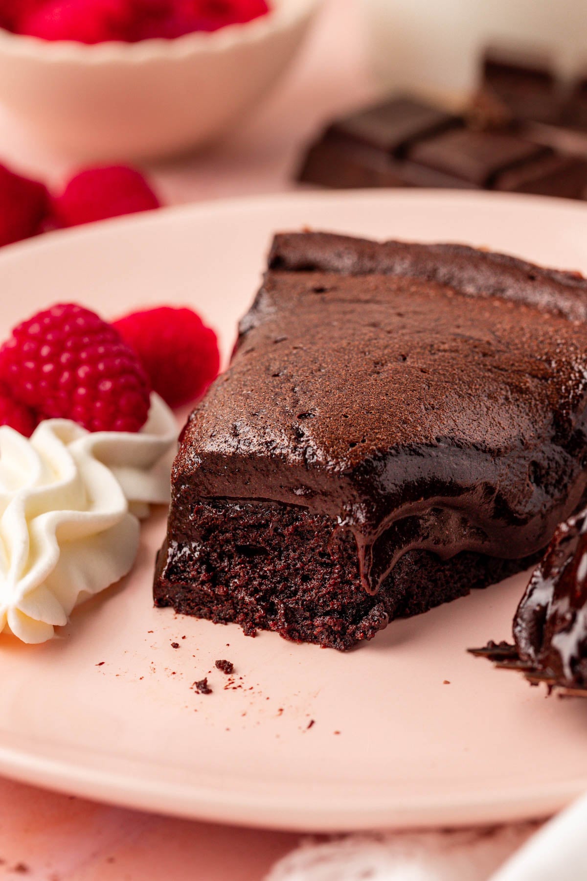 A slice of Meolleux au Chocolat cake on a pink plate with a bite missing.