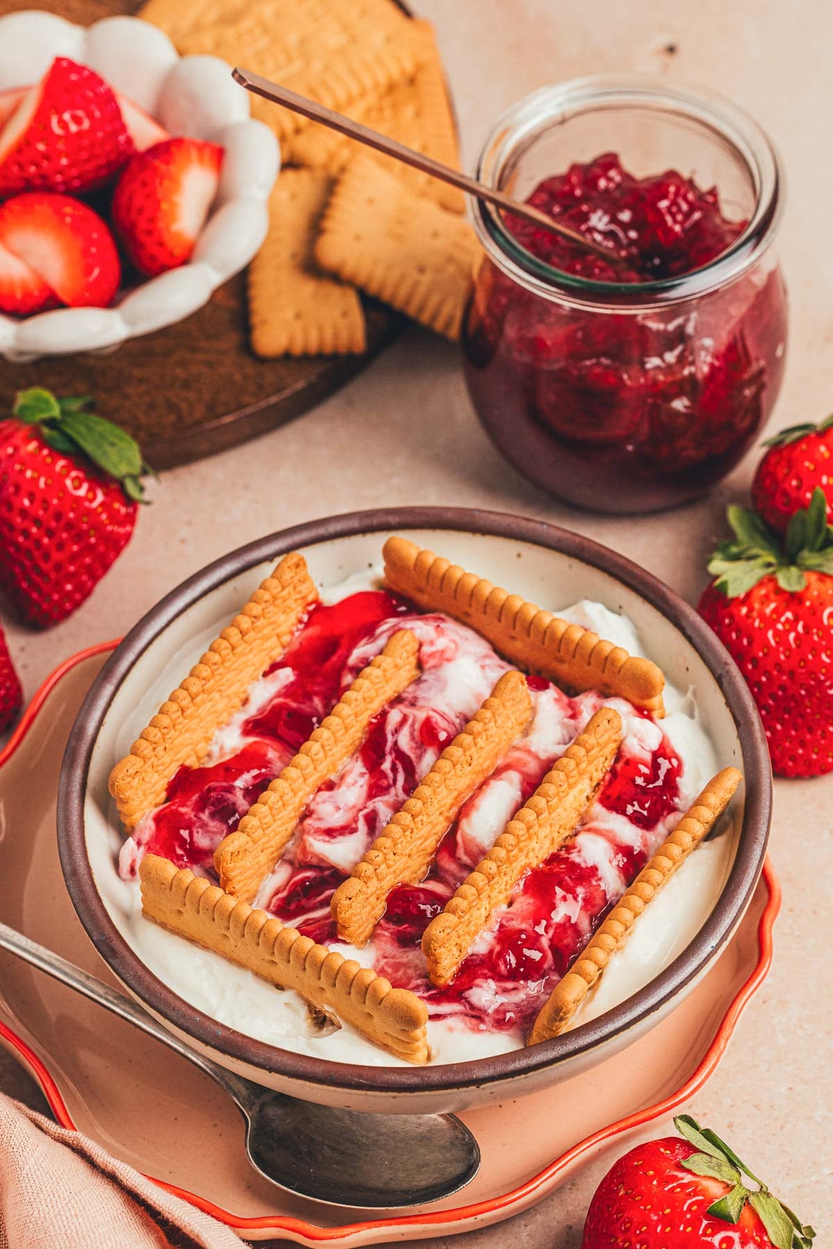A bowl of Japanese cheesecake with strawberry jam and biscuits sticking out.