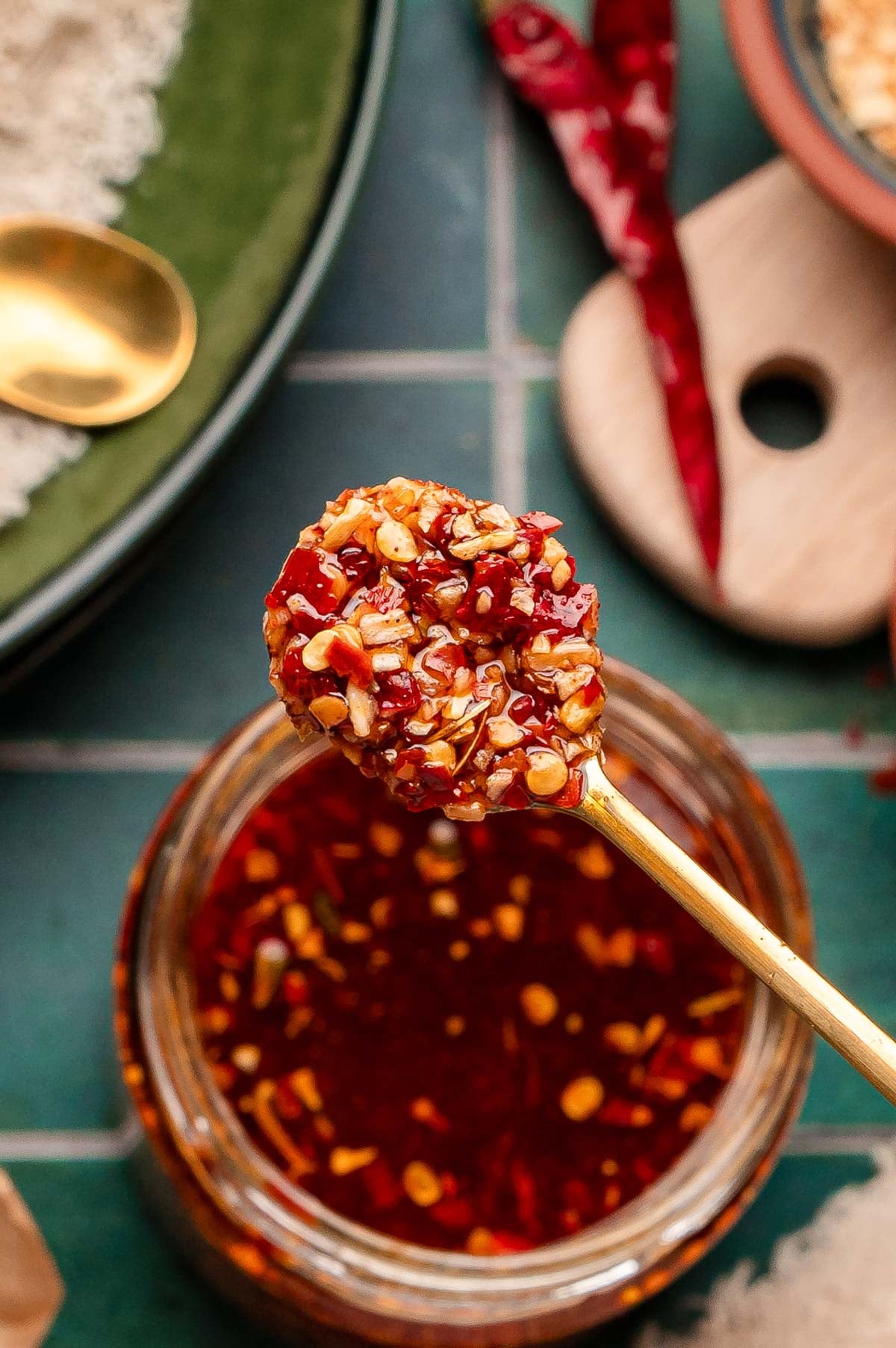 Overhead photo of a gold spoon scooping chili onion crunch out of a jar.