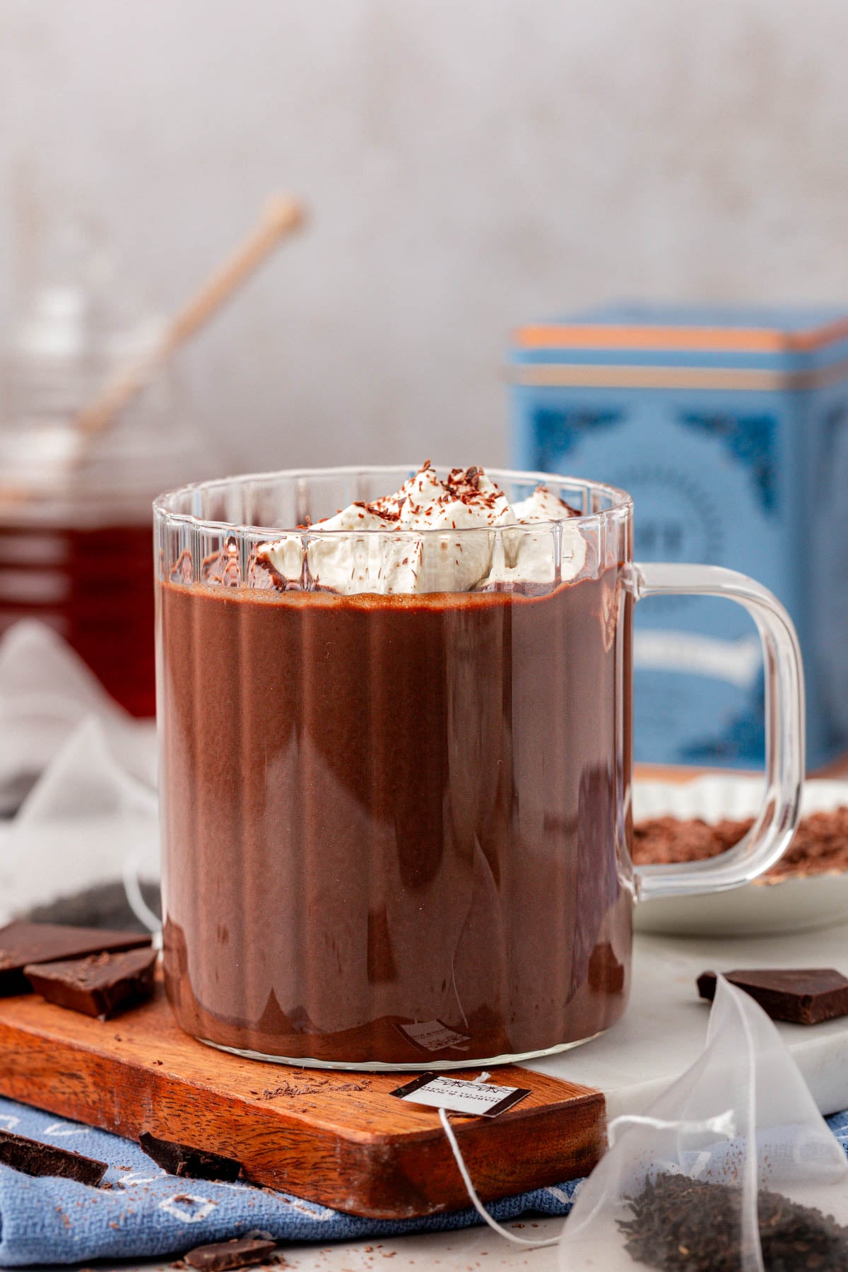 Hot chocolate in a clear mug on a wooden board.