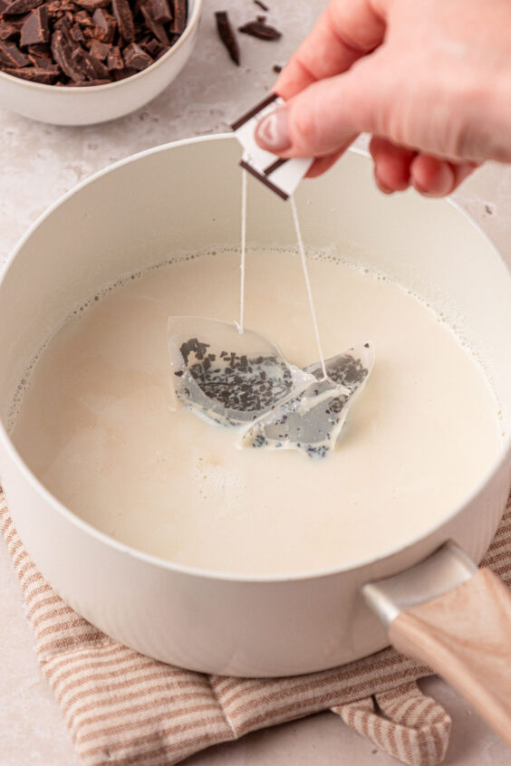 Two tea bags steeping in a pot of milk.