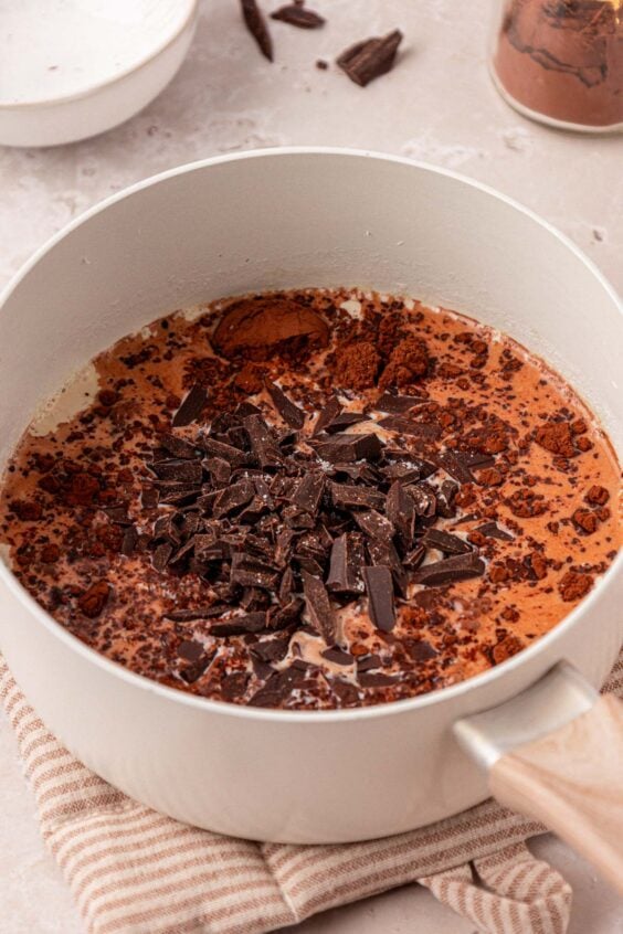 A pot of milk with chocolate and cocoa being added.