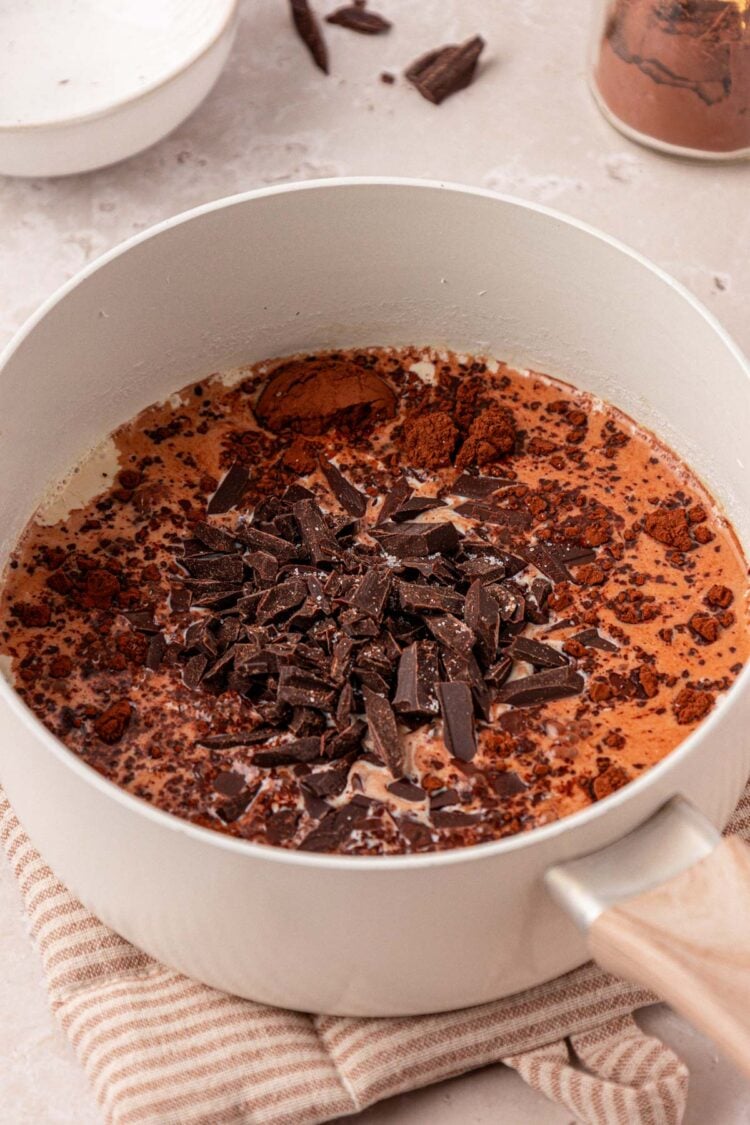 A pot of milk with chocolate and cocoa being added.