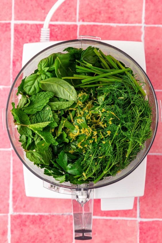 Herbs in a food processor to make green goddess dressing.