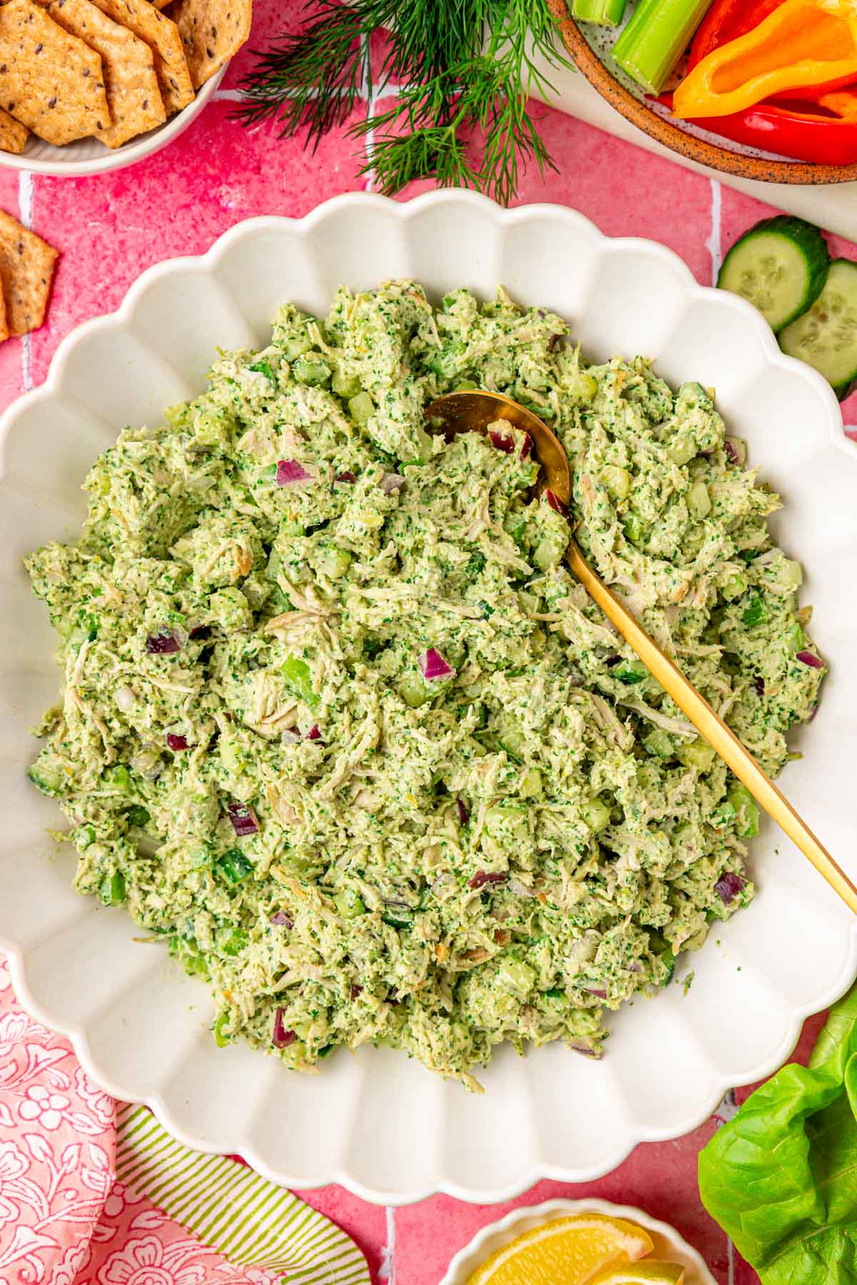 Overhead photo of a big white bowl of green goddess chicken salad on a pink table.