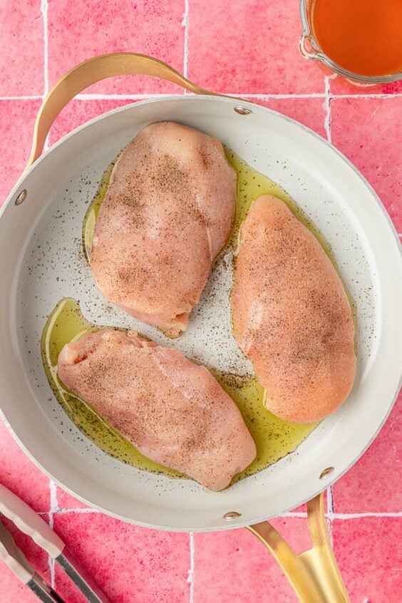 Chicken and oil in a skillet.