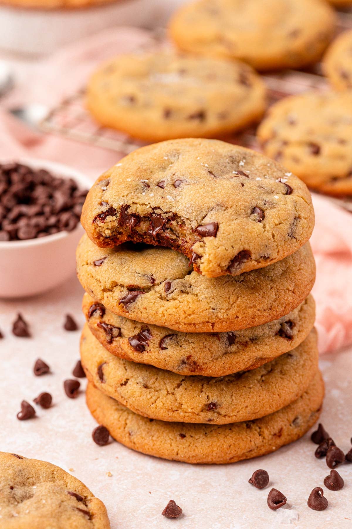 A stack of chocolate chip cookies. The top one is missing a bite.