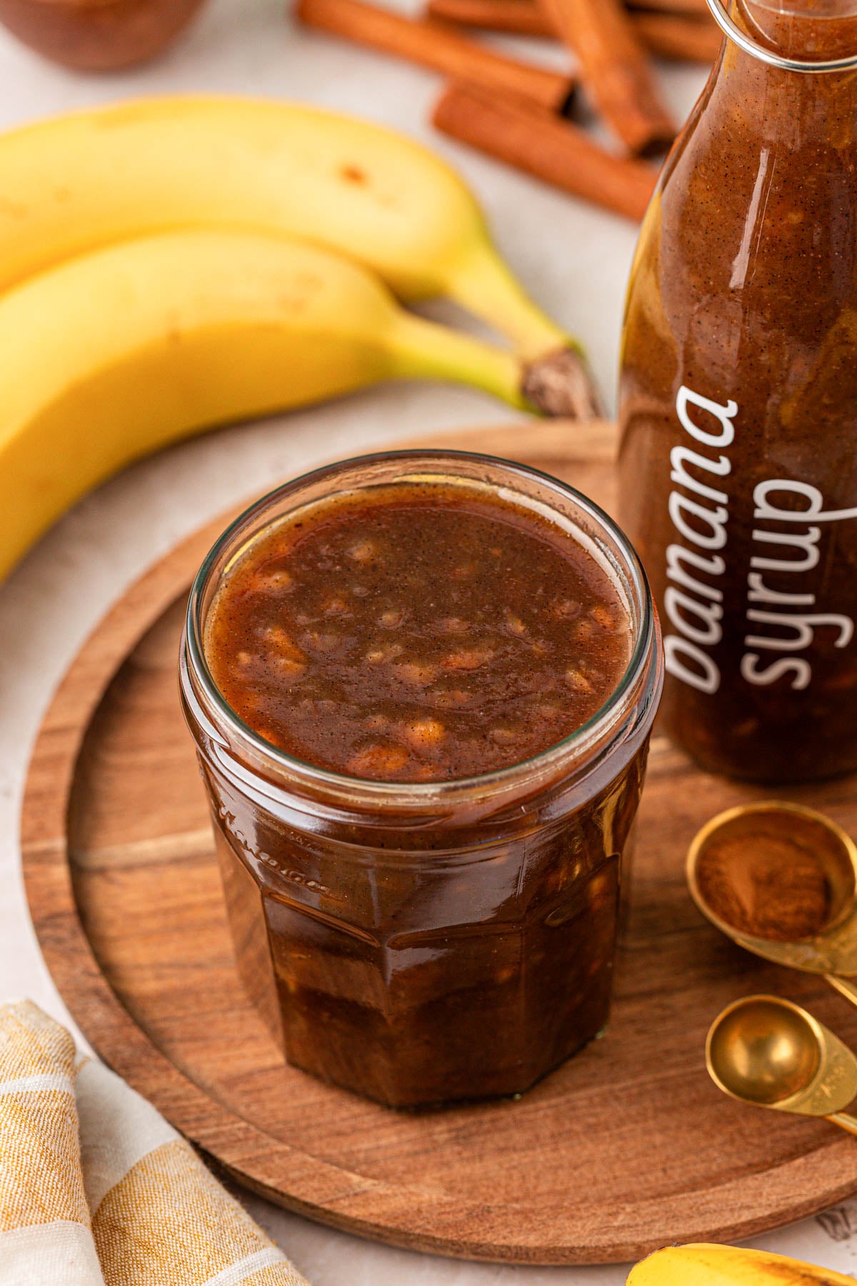 A jar of banana syrup on a wooden tray.