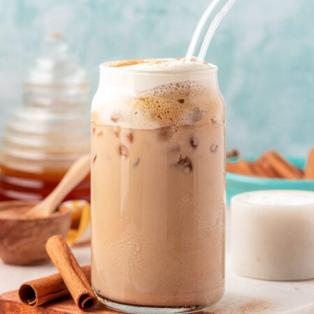 Close up of an iced salted honey latte in a glass with a straw.