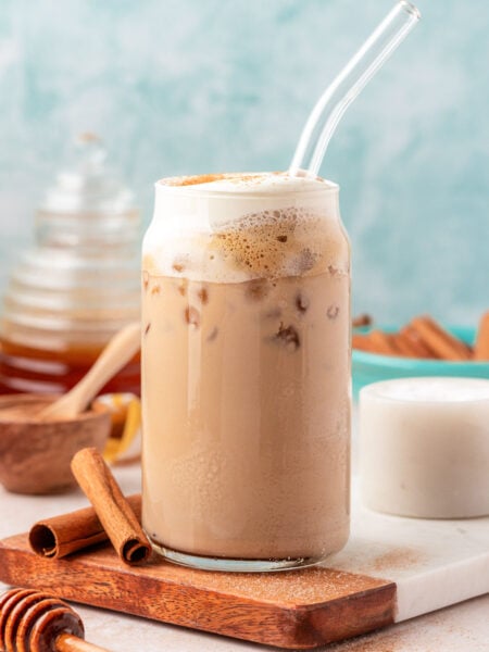 Close up of an iced salted honey latte in a glass with a straw.