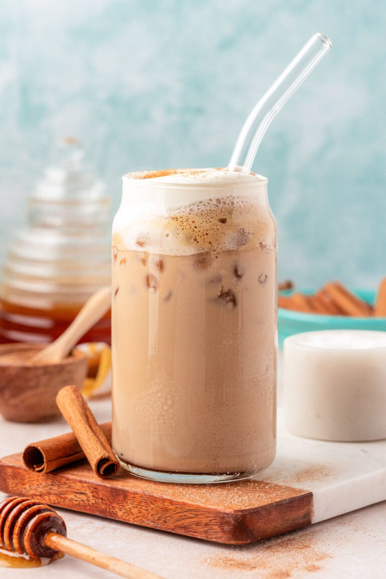 Close up of an iced salted honey latte in a glass with a straw.