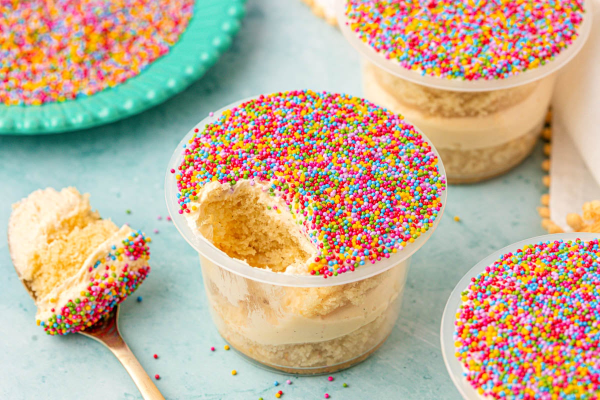Dot cakes on a table, one is missing a bit that is resting on a spoon next to it.