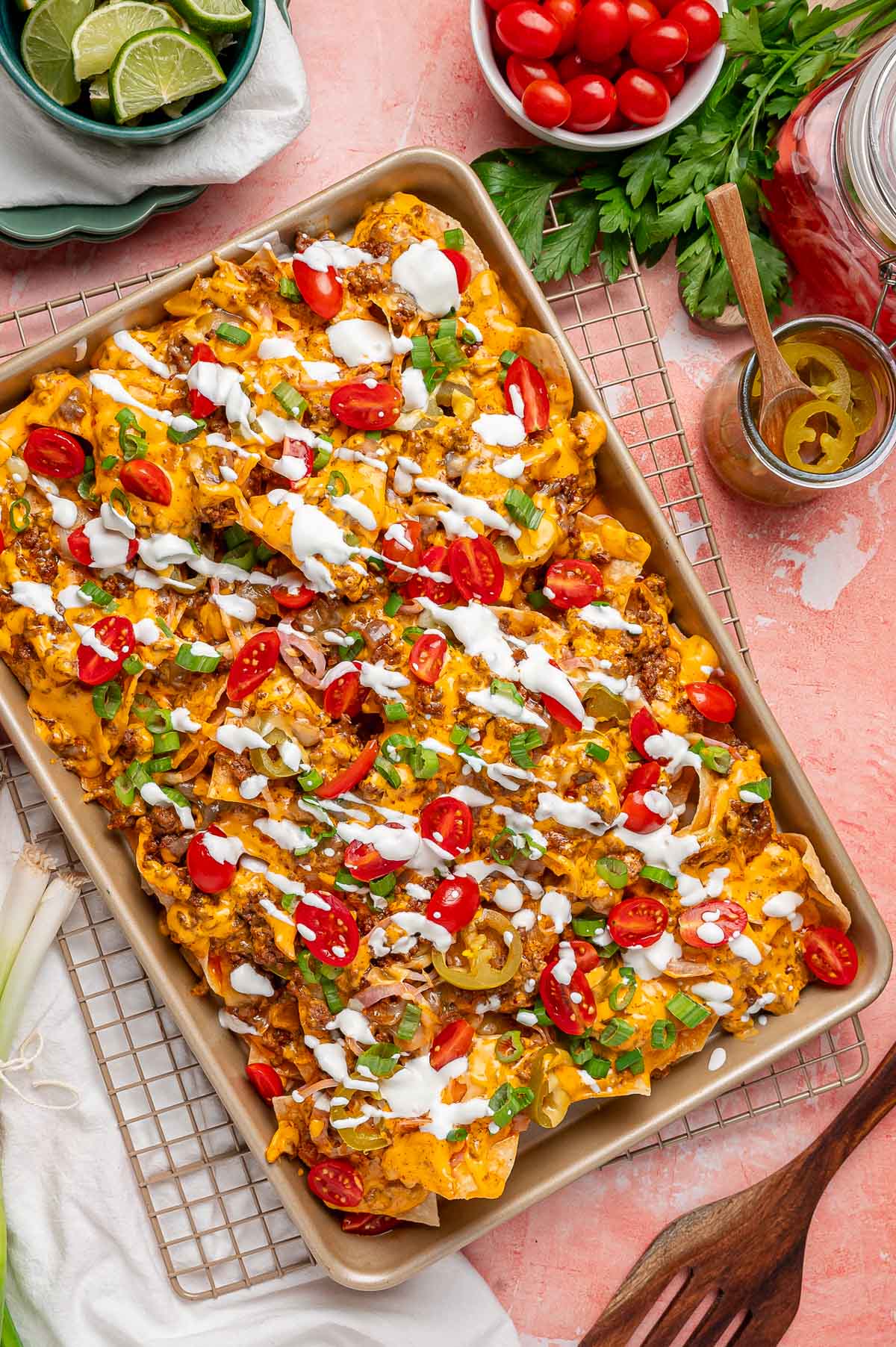 Overhead photo of a sheet pan with nachos on it on a pink table.