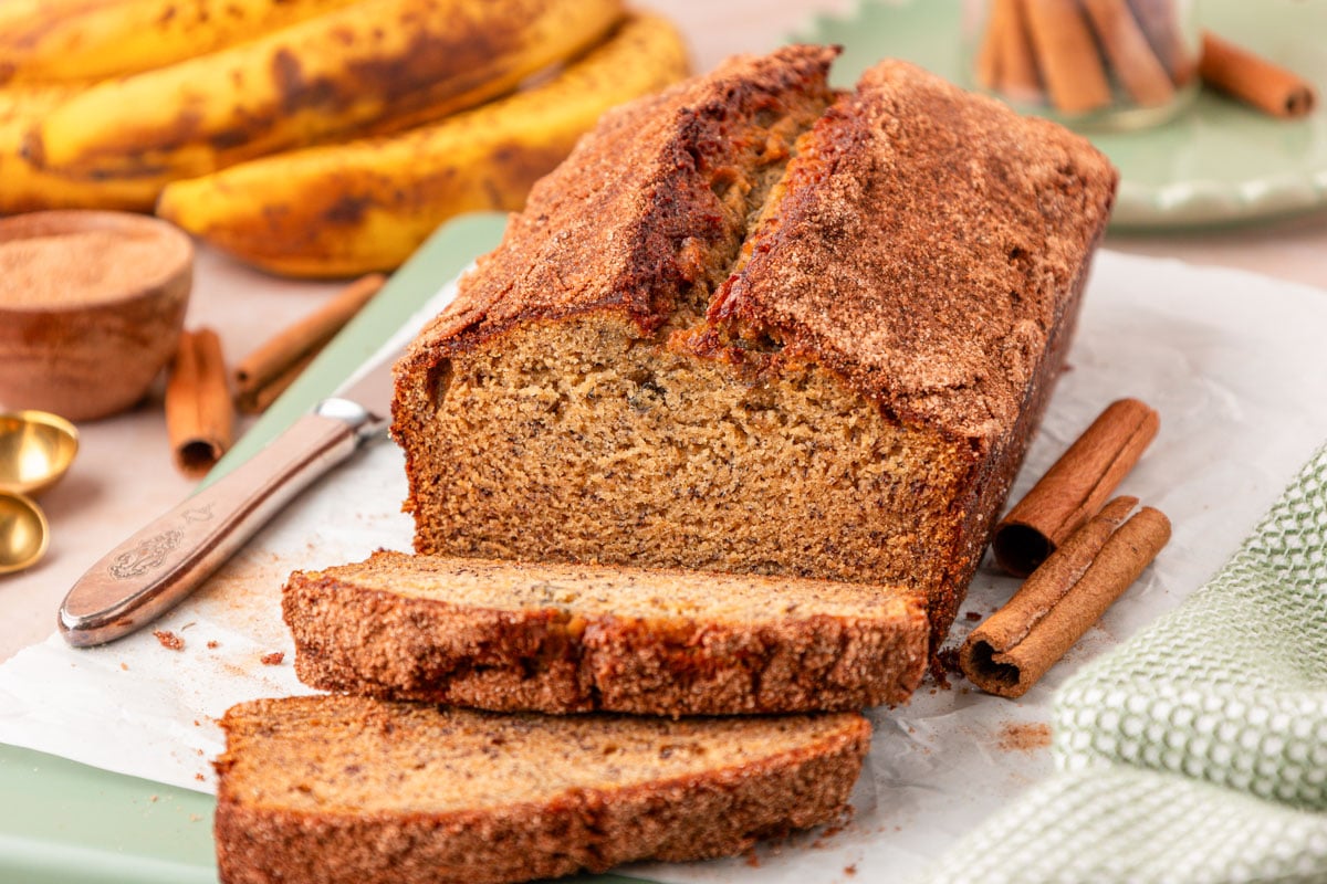 Slices of brown butter banana bread cut off a loaf on a cutting board.