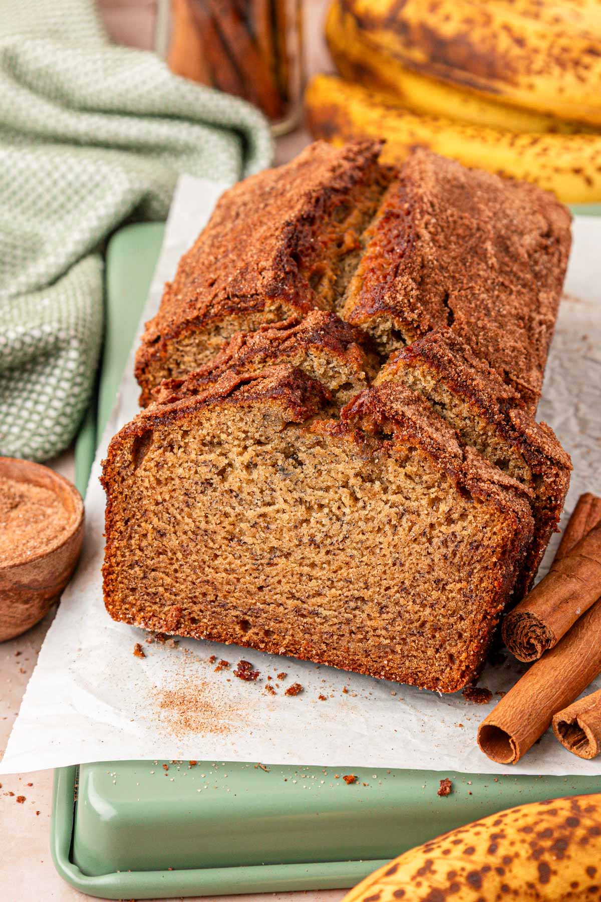 A loaf of banana bread with browned butter on a piece of parchment paper, some of it has been sliced.