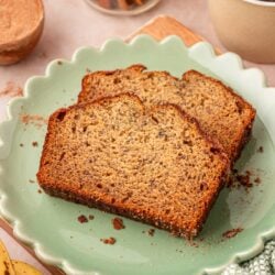 Two slices of banana bread on a scalloped green plate on a table.