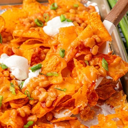 Margot Robbie's Bean Nachos being lifted off a pan with a spatula.