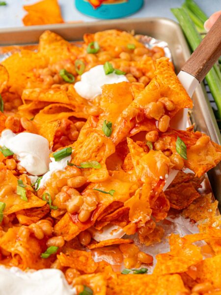Margot Robbie's Bean Nachos being lifted off a pan with a spatula.