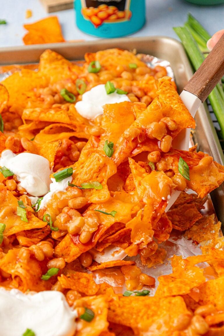 Margot Robbie's Bean Nachos being lifted off a pan with a spatula.