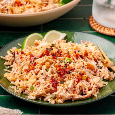 A green bowl filled with rotisserie chicken and rice bag mix.