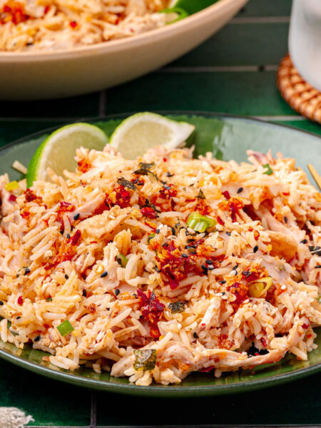 A green bowl filled with rotisserie chicken and rice bag mix.
