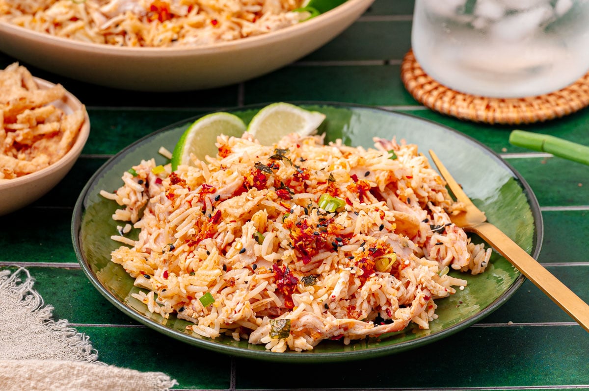 A green bowl filled with rotisserie chicken and rice bag mix.