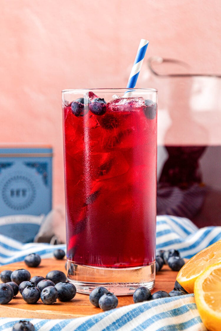A glass of blueberry iced tea on a wooden board.