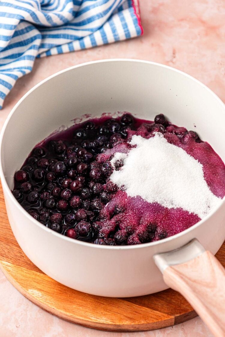Sugar, blueberries, and water in a saucepan.