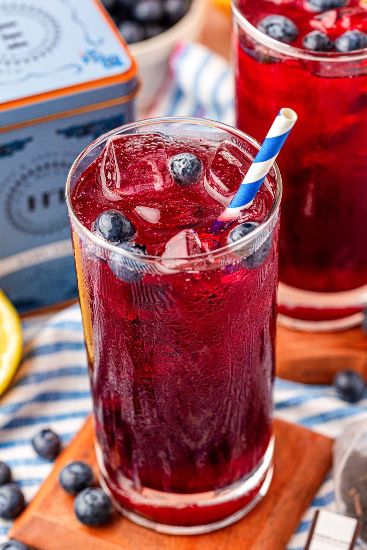 A glass of blueberry iced tea on a wooden coaster.