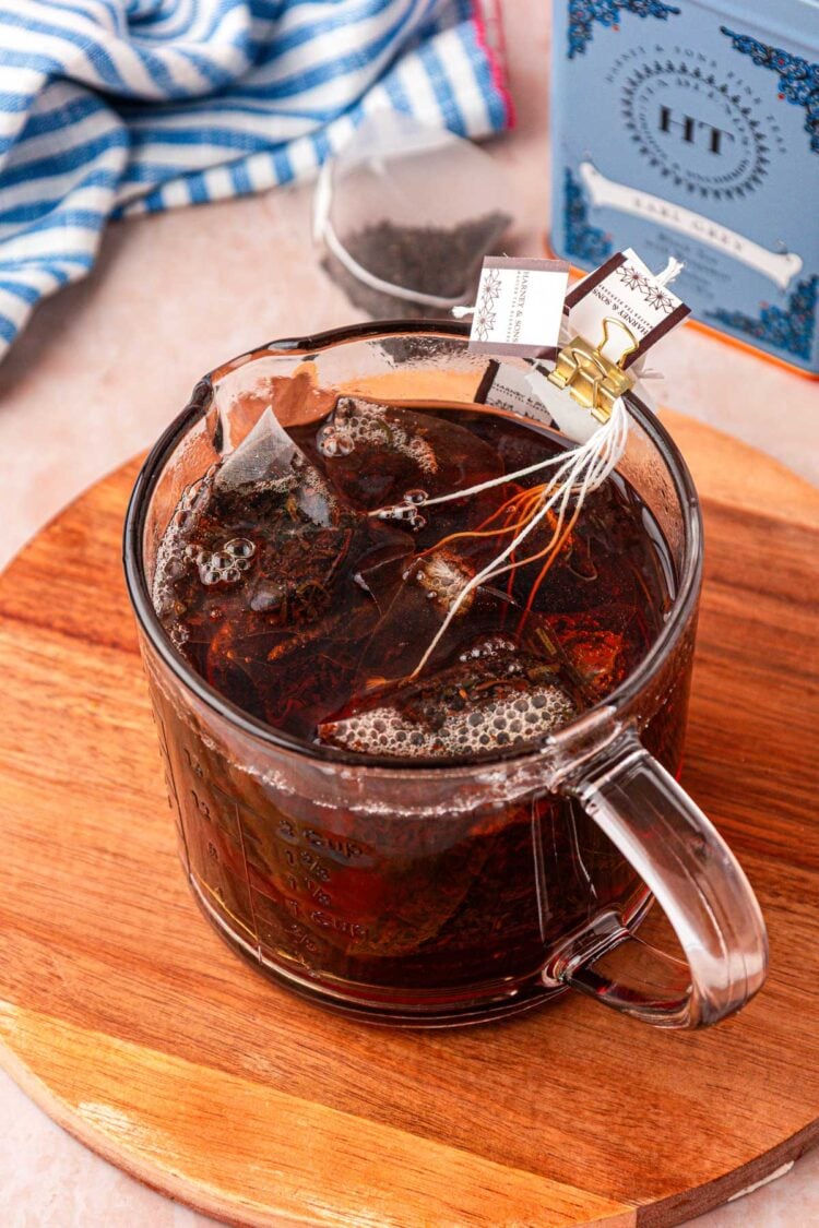Tea bags steeping in a clear glass mug.