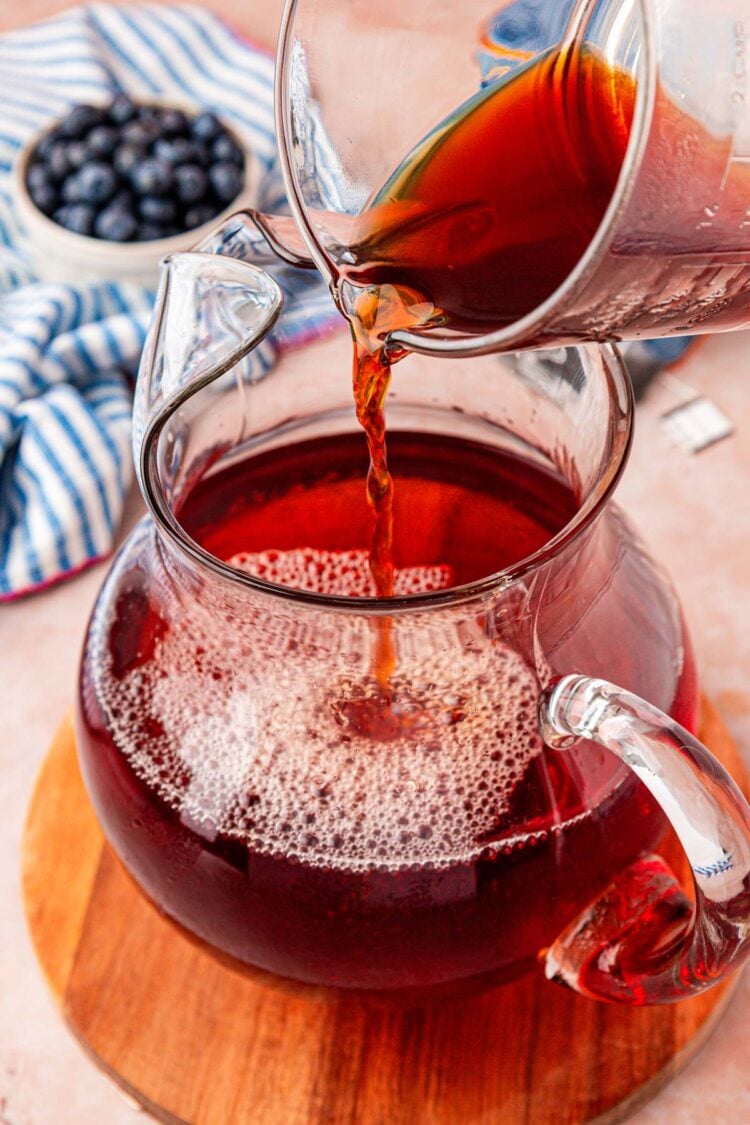 Tea being poured into a pitcher with water.