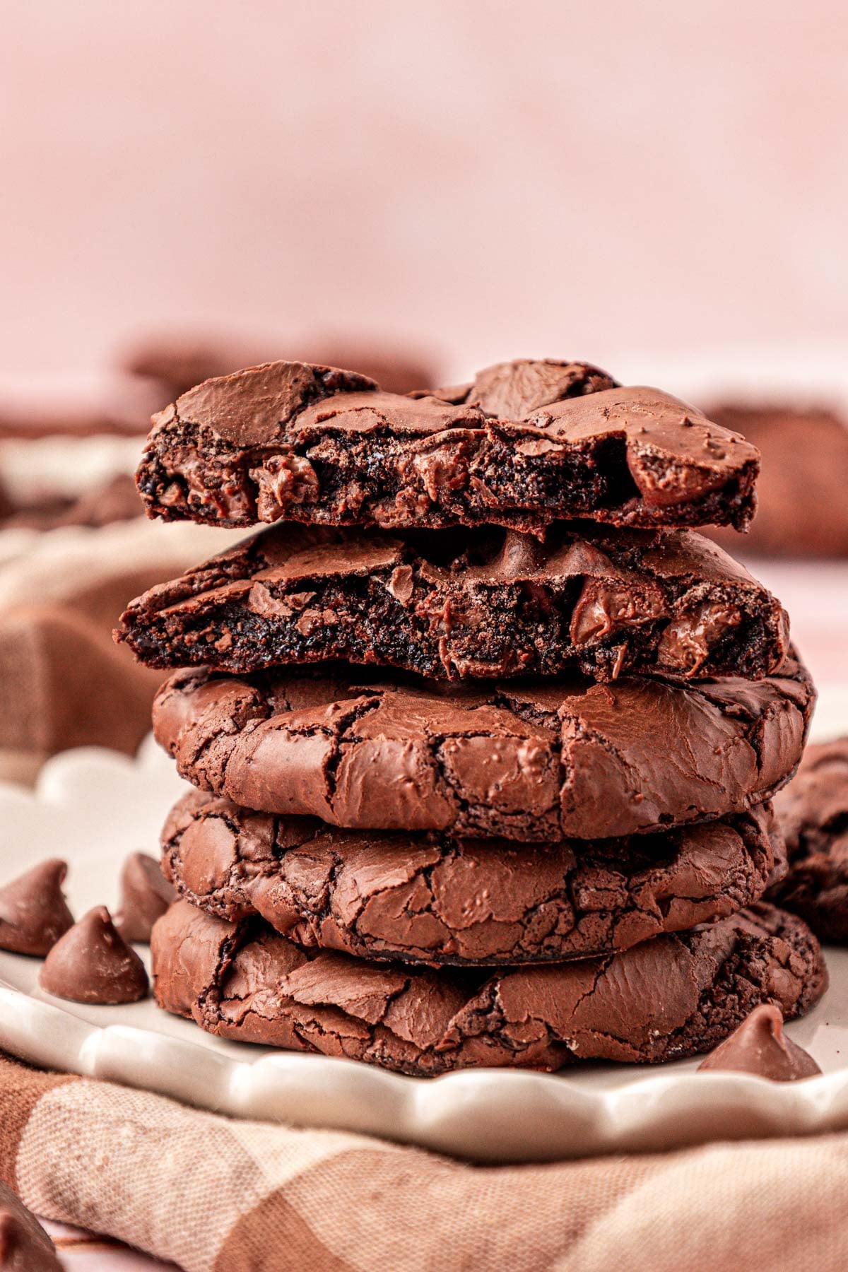 A stack of flourless brownie cookies, the top two are broken in half to show the gooey center.