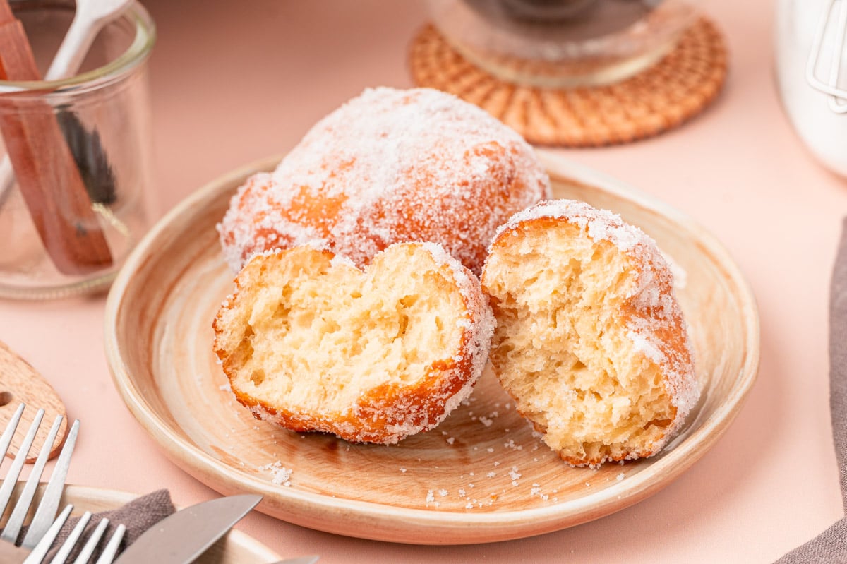 Close up of a plate on malasadas, one of them has been broken in half.